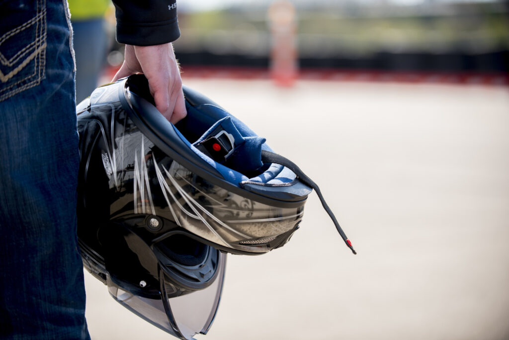 closeup-tiro-de-um-homem-segurando-seu-capacete-de-motocicleta-com-uma-distancia-borrada