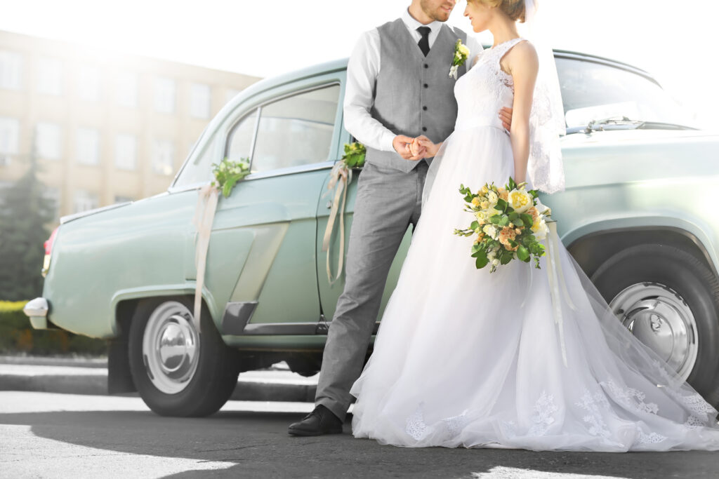 Happy wedding couple near decorated car outdoors